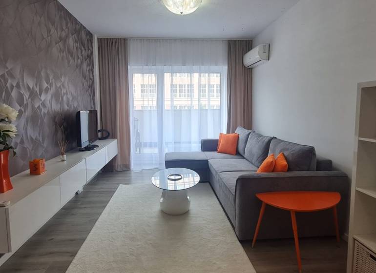 Living room with a sofa, television, and orange decorations in a two-room apartment.
