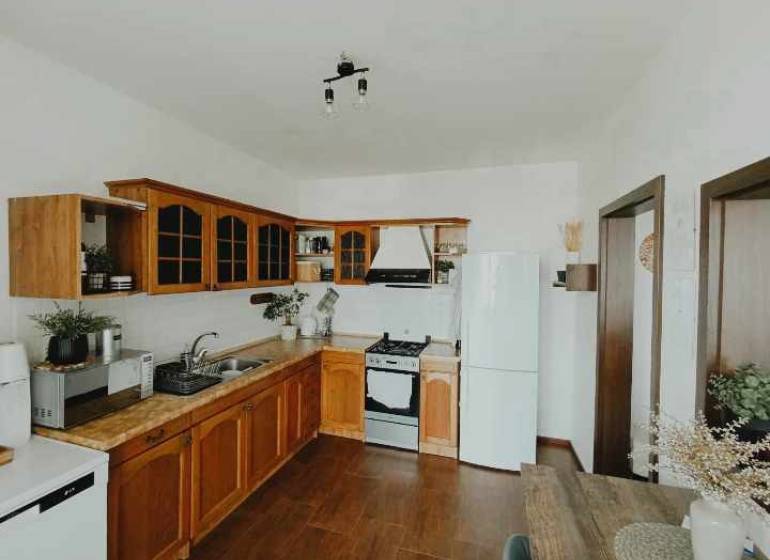 A kitchen in a 3-room apartment with wooden cabinets, a white refrigerator, and a stove.