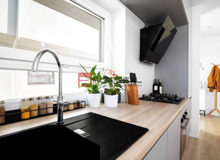 A kitchen in a 3-room apartment with a built-in hob and plants on the windowsill.