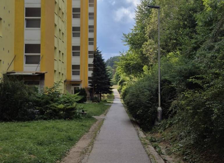 Yellow apartment building on Moskovská Street in Banská Bystrica next to the sidewalk and greenery.