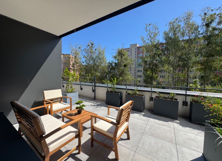 A terrace with wooden garden furniture surrounded by greenery on Popradská Street in Košice.