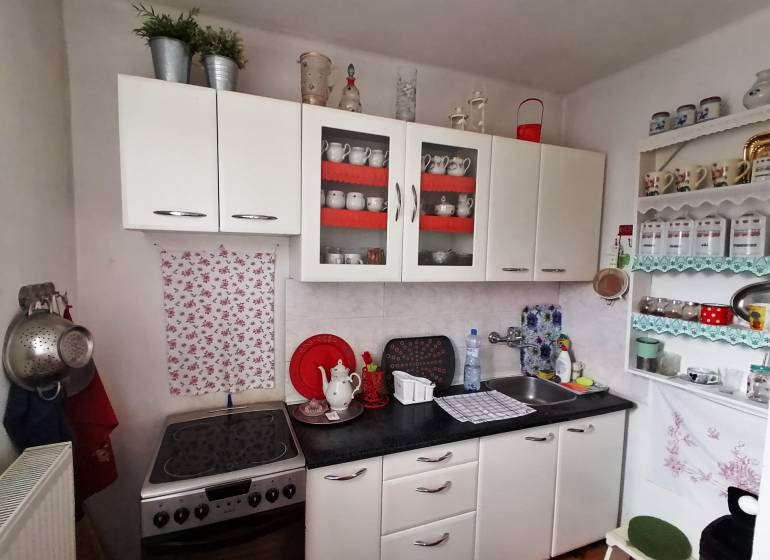 A kitchen in a 3-room apartment with white cabinets and decorative shelves.