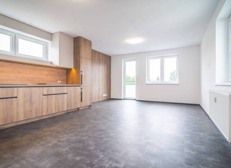 A kitchen in a 2-room apartment with a wooden decor floor and large windows.