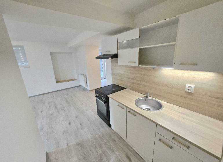 A kitchen with built-in cabinets and appliances in a 3-room apartment, flooring with a wood decor.