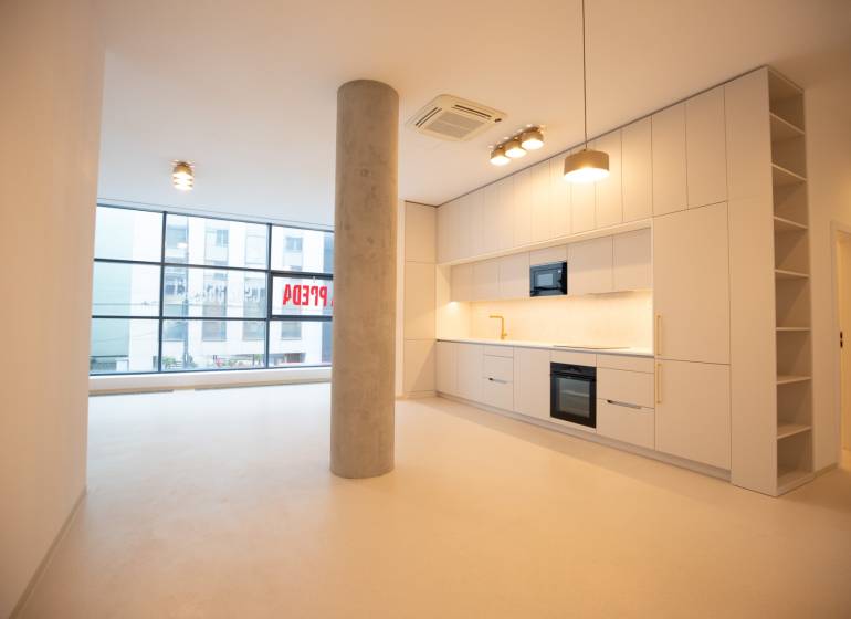 A kitchen in a 4-room apartment with white cabinets, a column, and large windows.