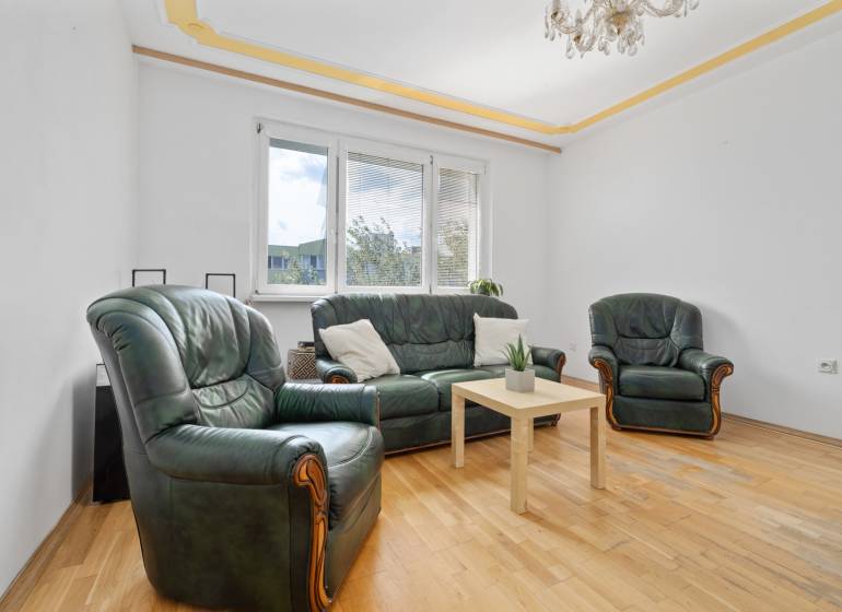 Living room in a 3-room apartment with a leather sofa set and a wooden table.