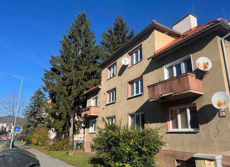 Apartment building on 9th May Street in Banská Bystrica, surrounded by trees and satellite dishes.