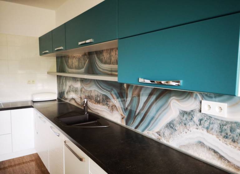 A kitchen in a 3-room apartment with a striking wall and a wooden decor floor.