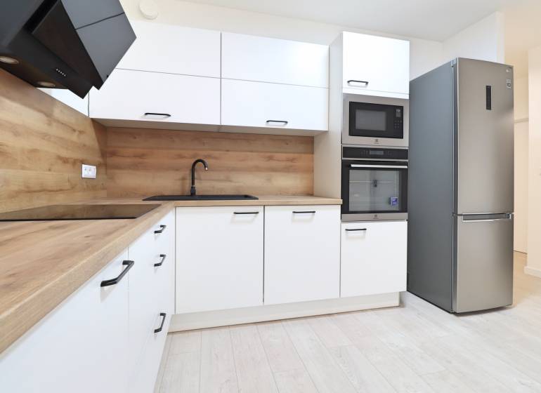 A kitchen in a 4-room apartment with modern appliances, wood-patterned flooring, and light-colored cabinets.