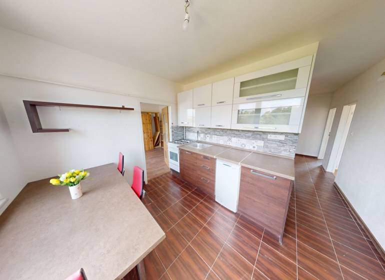The kitchen of a 4-room apartment with a wooden decor floor, a dining table, and cabinets.