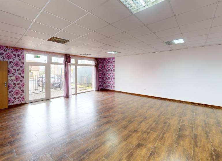 A spacious room in a family house with a wooden decor floor and floral wallpaper.