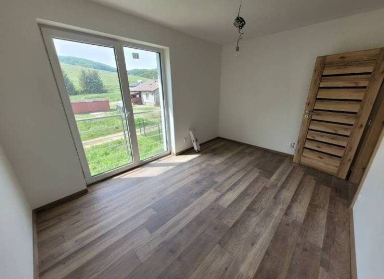 A room in a family house with a wooden decor floor and large windows.
