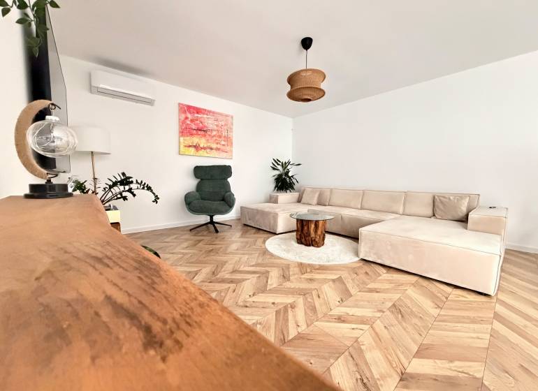 Living room with a large sofa, an armchair, and a wooden decor floor in a family house.