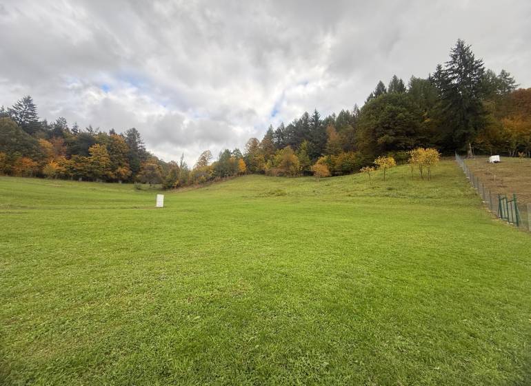 A woman in front of a construction plot in Zbora, Zbora Street, with contact information.
