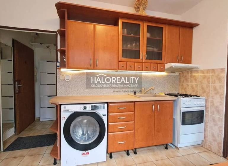 Kitchen unit with wood decor, washing machine and stove in a studio apartment.