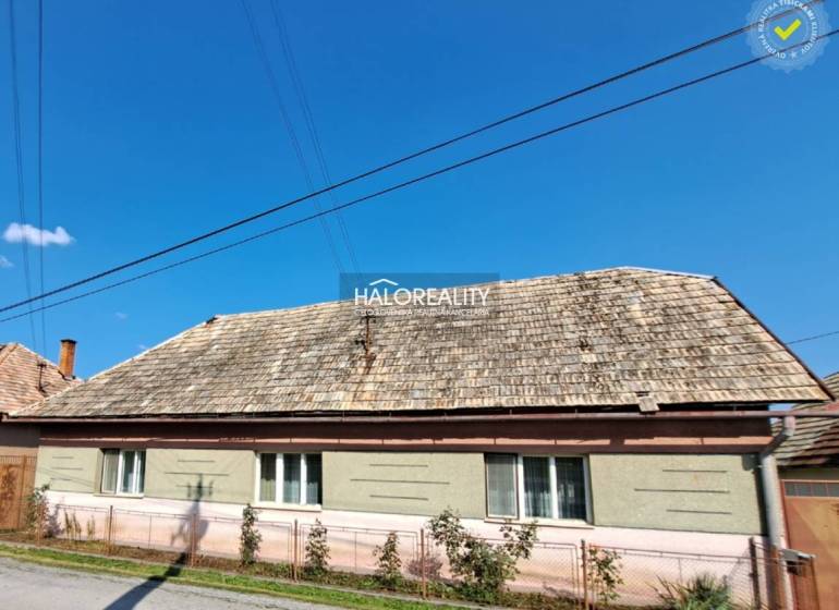 A family house in Zvolen with a gable roof and a wooden fence in front of the house.