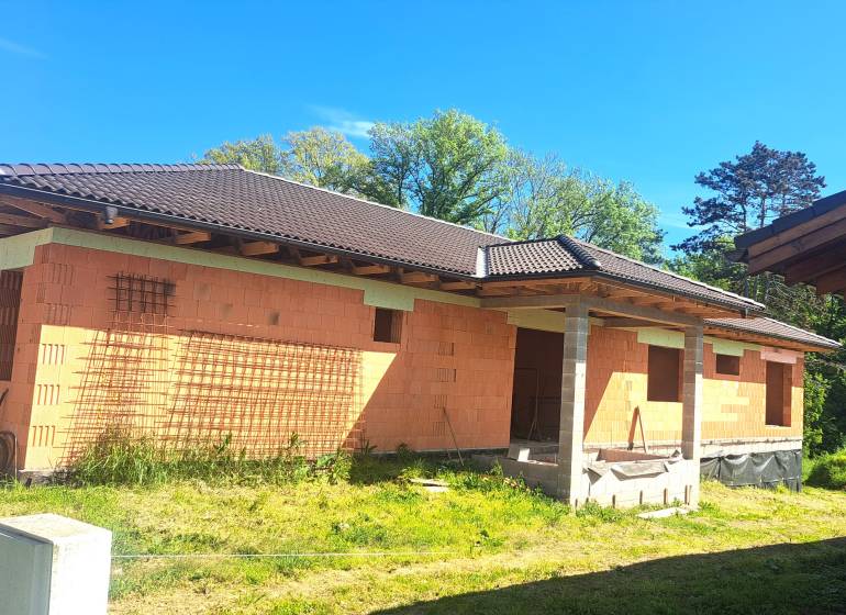 Family house in Hokovce under construction with a roof and brick walls.