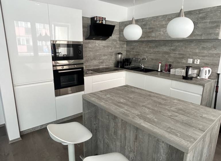 A kitchen in a 2-room apartment with a kitchen island and a floor with a wooden decor.
