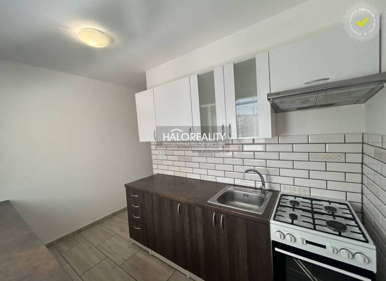 A kitchen in a 3-room apartment with white tiles and a wooden decor floor.