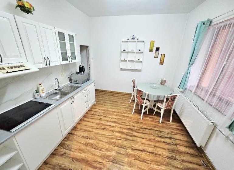 A kitchen in a family house with a wooden decor floor, a table, and white cabinets.