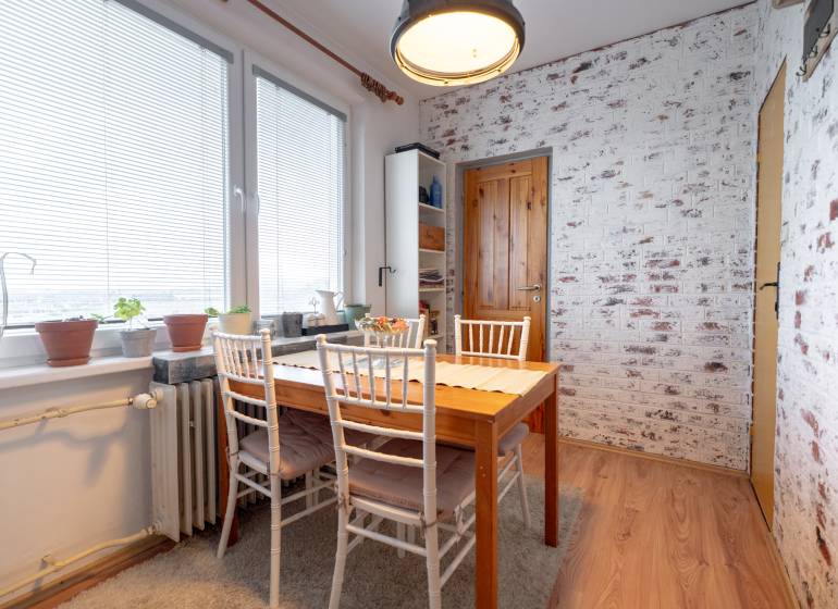 Dining area in a 3-room apartment with a brick wall and a wooden decor floor.