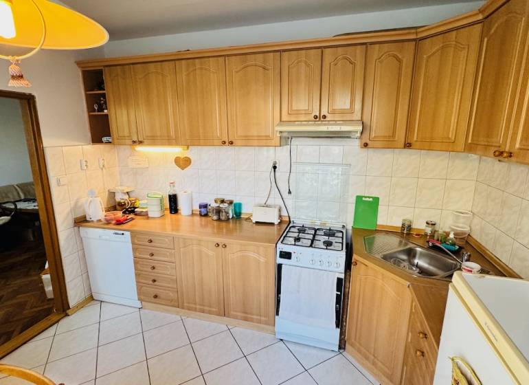 A kitchen with wooden decor, appliances, and a corner sink in a 3-room apartment.