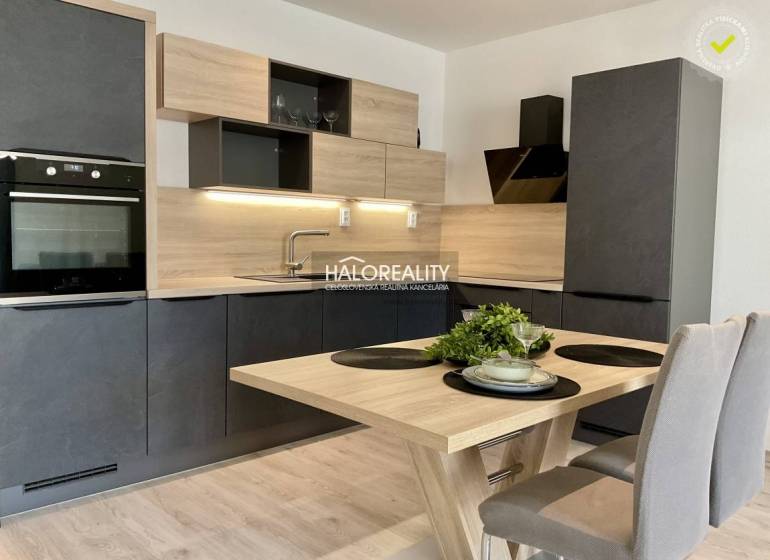 A kitchen in a 3-room apartment with a wood-patterned floor, black cabinets, and wooden accessories.