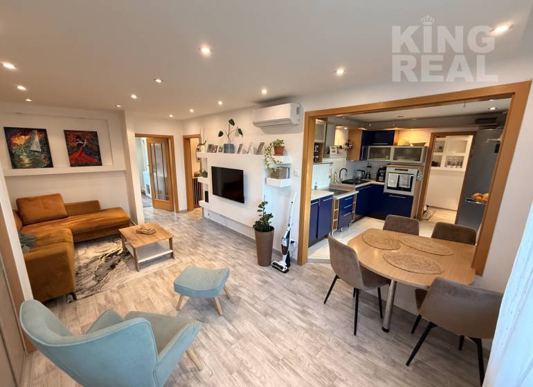 Living room with kitchen in a 3-room apartment, wooden decor flooring, comfortable seating.