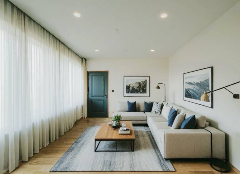 Living room with a glossy wooden-patterned floor, a sofa, and a coffee table in a three-room apartment.