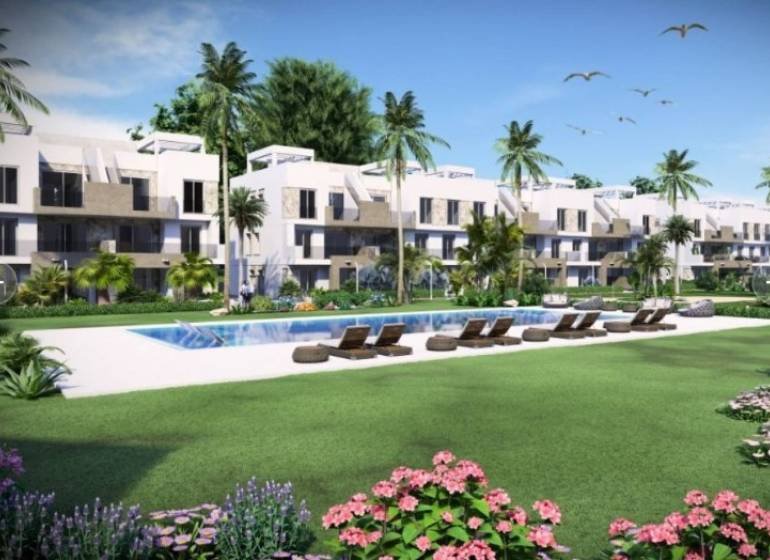 Recreational apartment in Guardamar del Segura with a pool, palm trees, and sun loungers in the garden.