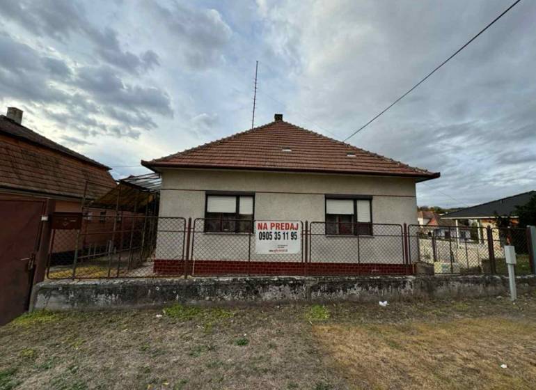 A family house in the center of Veľké Lovce with a brick roof and fencing.