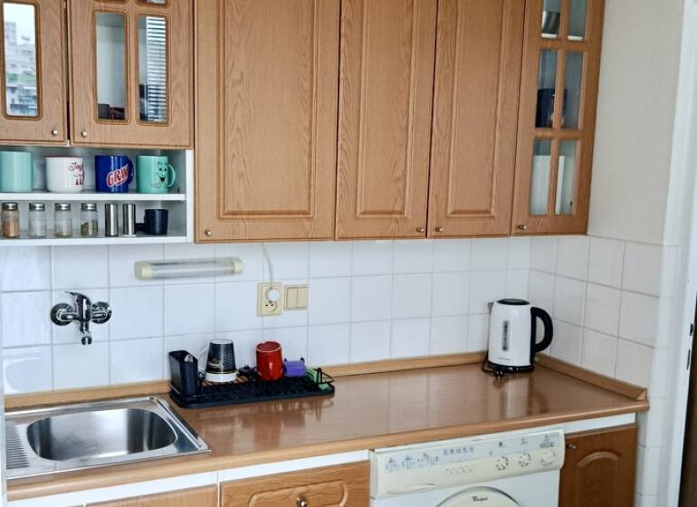 Kitchen unit with wood decor, built-in oven and washing machine in a studio apartment.