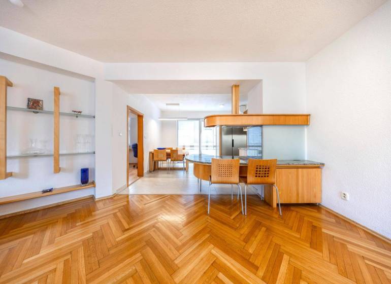 Interior of a 3-room apartment with wood-patterned flooring, a dining area, and an open kitchen.