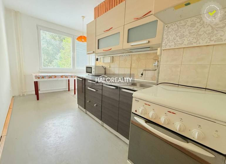 A kitchen in a 2-room apartment with simple furniture and a large window.