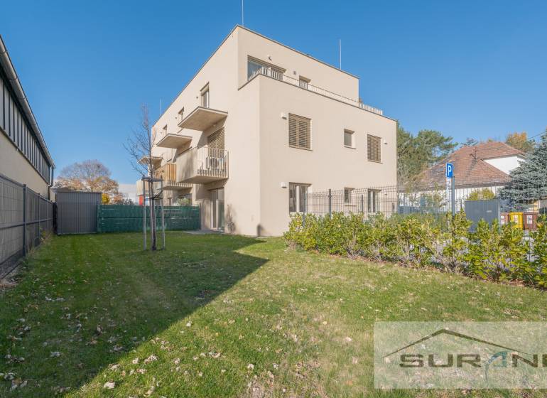 A building with two floors, green grass, and blue sky on Železničná Street in Bratislava.