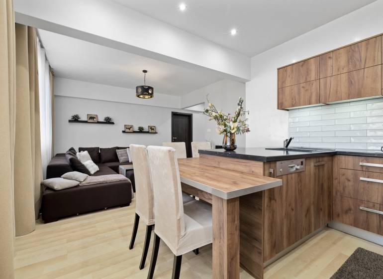 Living room and kitchen with wood-patterned flooring in a two-room apartment.