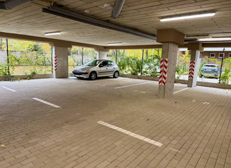 Spacious parking in garages on Sadova Street in Senica with a car and pillars.