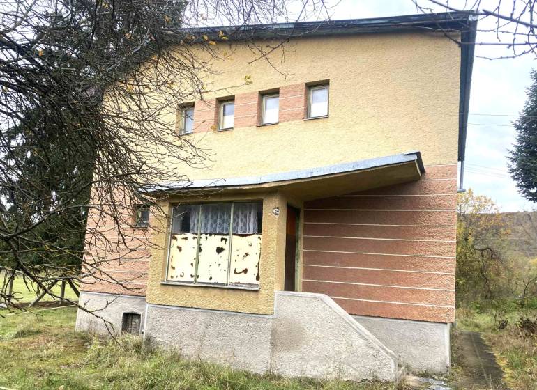 A family house in Rykynčice with colorful plaster, a sloped roof, and shutters.