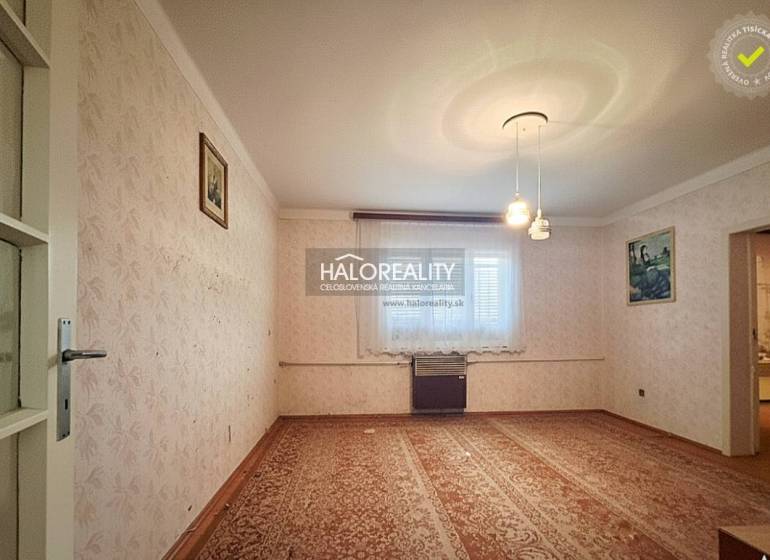Living room in a family house with carpet, wallpaper, and wall paintings.
