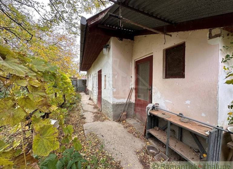 The exterior of a family house in Zemné with old plaster and a shelter.