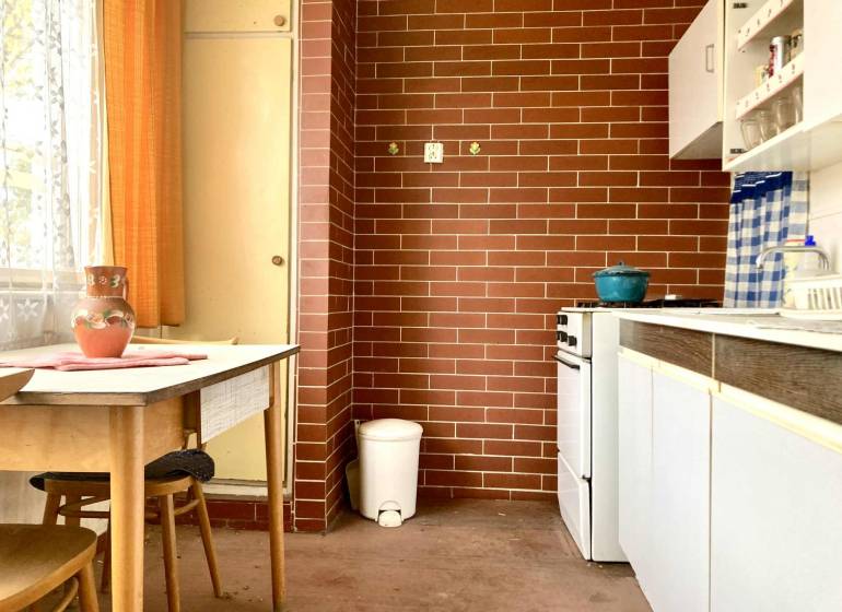 A kitchen in a 3-room apartment with red brick cladding and a wooden table.