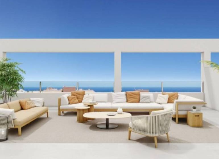 Terrace of a recreational apartment in Torrevieja with seating, ocean and blue sky in the background.