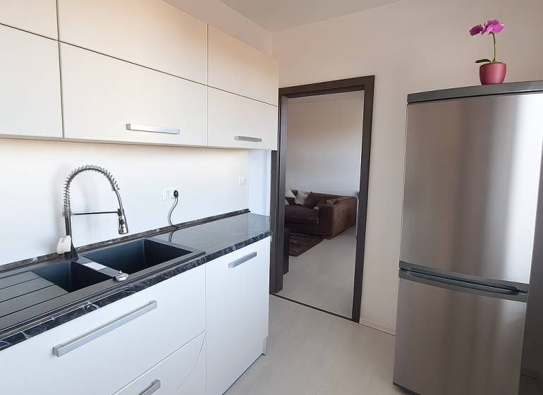 Kitchen in a 3-room apartment with a stainless steel refrigerator and a countertop, floor with wood decor.