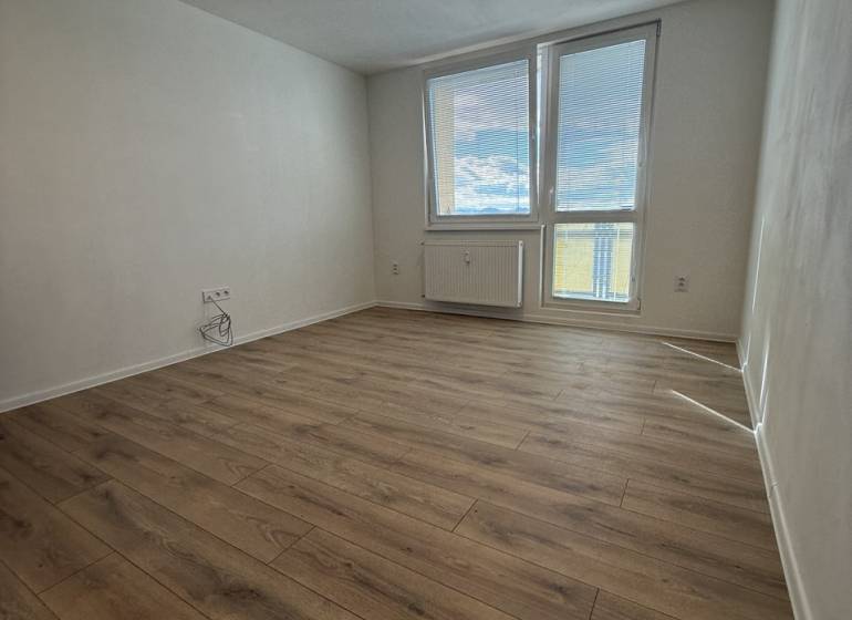 A room with a wooden floor decor, large window and radiator, studio apartment.