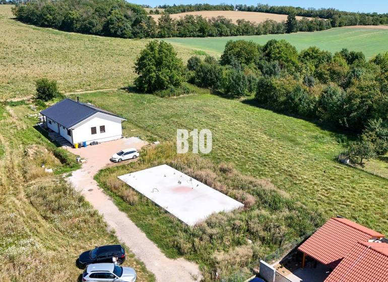 A plot of land for living in Čeľadice includes a house, greenery, and cars.