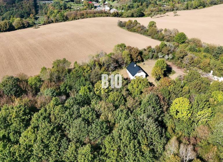A cottage in Lackov surrounded by forest and fields, a peaceful rural landscape.