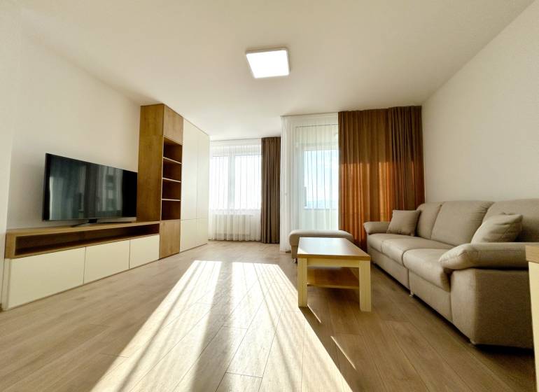 Living room with a sofa, television, table, and wooden decor flooring in a 2-room apartment.