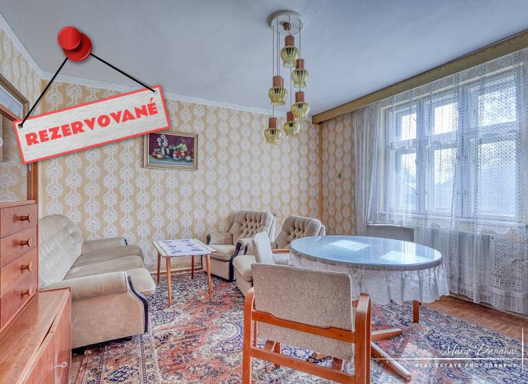 Interior of a family house with vintage furniture, wallpaper, and a large window with a lace curtain.