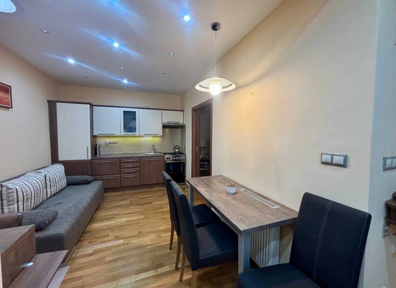 Kitchen corner with dining area in a studio apartment with a wood-patterned floor.