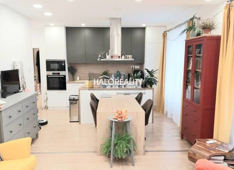 A kitchen in a 3-room apartment with a wooden decor floor, a dining table, and a bookshelf.